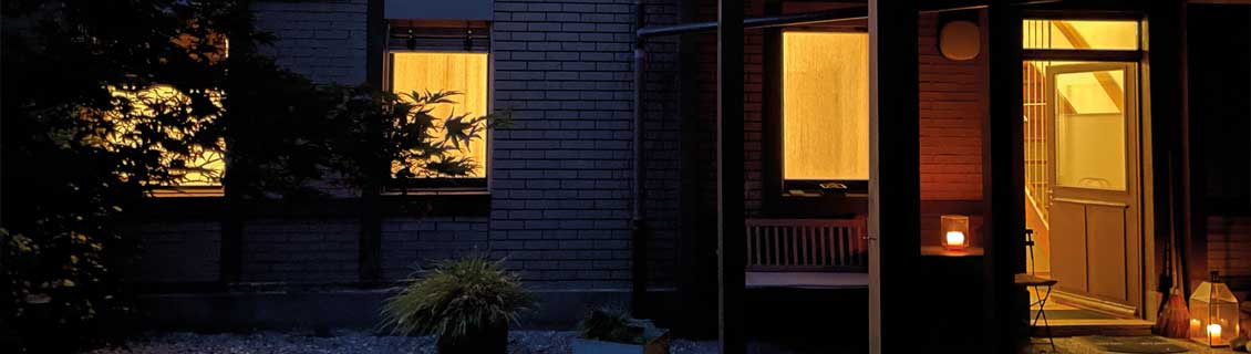 Schamanische Heilnacht in Basel: Erleuchtetes Hinterhaus bei Nacht mit offener Tür und zwei einladenden Laternen.